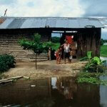 family standing outside of a home near the water